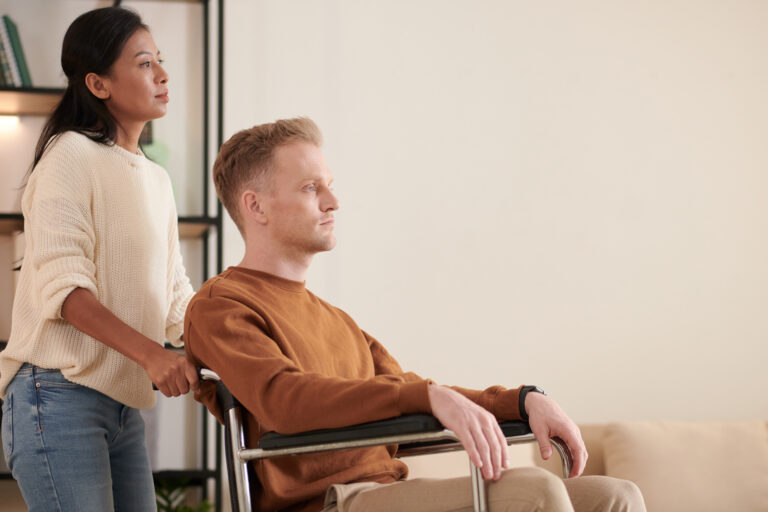 Female caregiver pushing patient sitting in wheelchair